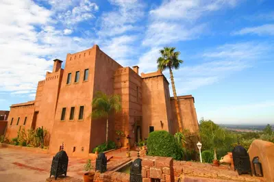 a building with a palm tree in front of it at Kasbah Agounsane Hotel & Spa in Ourika