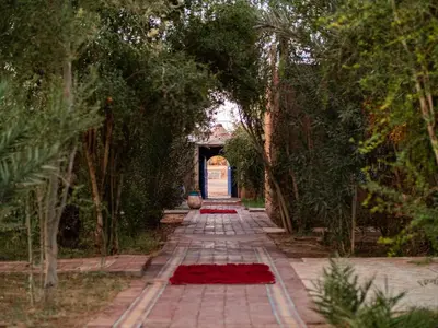 a walkway with trees and red flowers on it at Hamada Du Draa in Mhamid