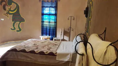 a bedroom with a bed with a painting on the wall at Hamada Du Draa in Mhamid