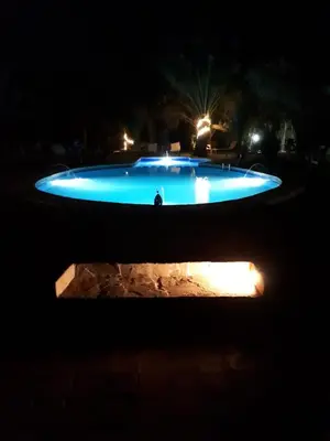 a blue swimming pool at night with lights at Hamada Du Draa in Mhamid