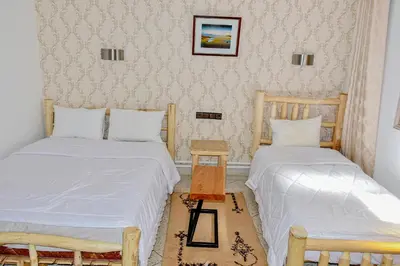 two beds in a room with two chairs and a table at Hotel Safari Week end in Midelt