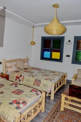 two beds in a room with colorful windows at Hotel Safari Week end in Midelt