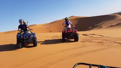 two people riding on atvs in the desert at Camp Under Stars in Merzouga