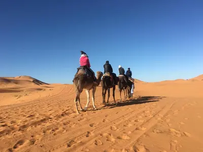 a group of people riding horses in the desert at Camp Under Stars in Merzouga