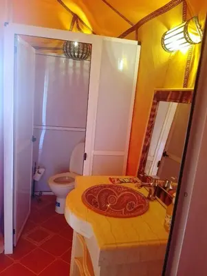 a bathroom with a sink and a toilet and a mirror at Camp Under Stars in Merzouga