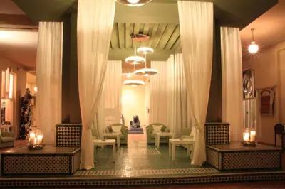 a lobby with tables and chairs and curtains at Berbère Palace in Ouarzazate