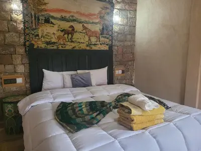 a white bed with towels and a painting on the wall at Chambre d'hôtes aya in Ouzoud