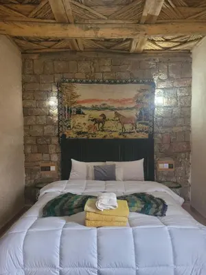 a bedroom with a large white bed with a painting on the wall at Chambre d'hôtes aya in Ouzoud