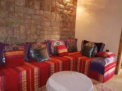 a couch with colorful pillows sitting next to a brick wall at Chambre d'hôtes aya in Ouzoud