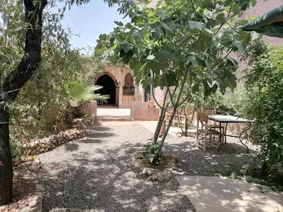 a garden with a table and a tree in front of a building at Chambre d'hôtes aya in Ouzoud