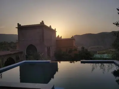 a house with a swimming pool in front of a sunset at Chambre d'hôtes aya in Ouzoud