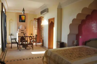 a bedroom with a bed and a table and chairs at Citadelle d'Orient in Aghmat