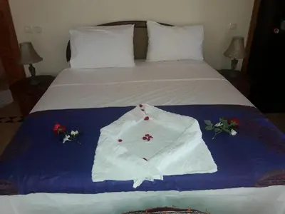 a bed with a white robe with flowers on it at Citadelle d'Orient in Aghmat