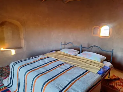 a bed with a striped blanket and two pillows at M'hamid Desert Camp Tours in Mhamid