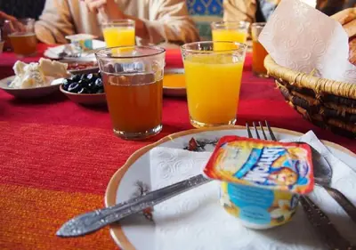 a table with a plate of food and two glasses of orange juice at M'hamid Desert Camp Tours in Mhamid