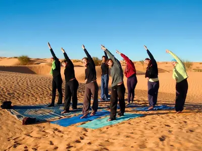 a group of people doing yoga in the desert at M'hamid Desert Camp Tours in Mhamid