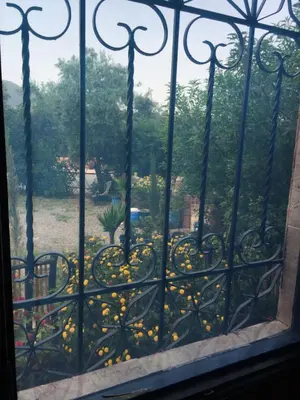 a window with a view of a garden with yellow flowers at Dar Marwa in Ouzoud