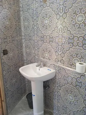 a white sink in a bathroom with wallpaper at Dar Marwa in Ouzoud