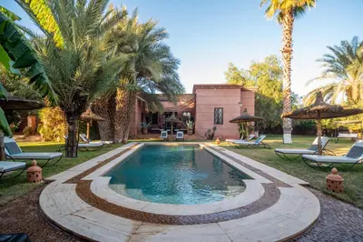 a swimming pool in front of a house with palm trees at Villa Septha in Marrakech
