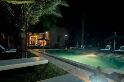 a swimming pool at night with a palm tree at Villa Septha in Marrakech