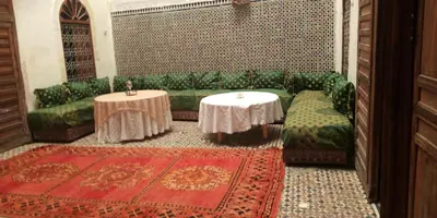 a living room with a green couch and two tables at Dar Ouassim in Fès