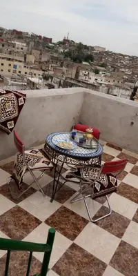 a table and chairs on a balcony with a view of a city at Dar Ouassim in Fès