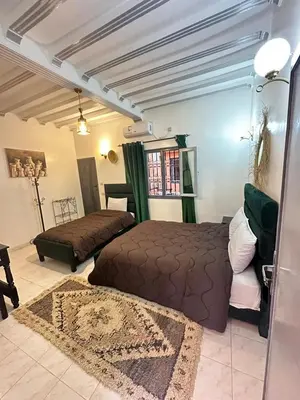 a bedroom with two beds and a couch at Hôtel Zaghro in Ouarzazate