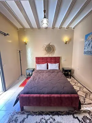 a bedroom with a large bed with a red headboard at Hôtel Zaghro in Ouarzazate