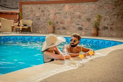 a man and woman sitting in a swimming pool with wine glasses at Ouednoujoum Ecolodge & Spa in Ouarzazate