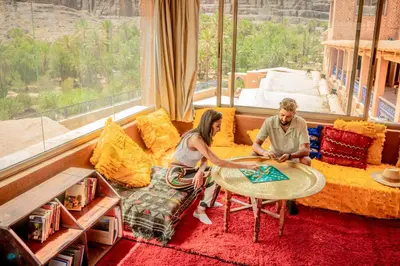 a man and woman sitting at a table in a living room at Ouednoujoum Ecolodge & Spa in Ouarzazate