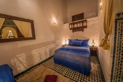 a bedroom with a blue bed and a mirror at Riad Gzira Fez in Fès