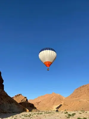 a hot air balloon flying over the desert at Riad Dar Bab Todra in Tinerhir