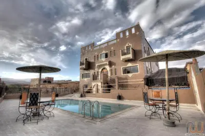 a resort with a pool and chairs and umbrellas at Riad Dar Bab Todra in Tinerhir