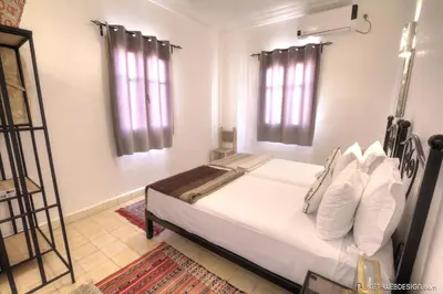 a bedroom with a bed with white sheets and pillows at Riad Dar Bab Todra in Tinerhir
