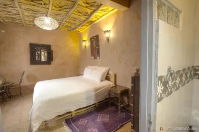 a bedroom with a white bed and a table at Guest House Bagdad Café in Aït Ben Haddou