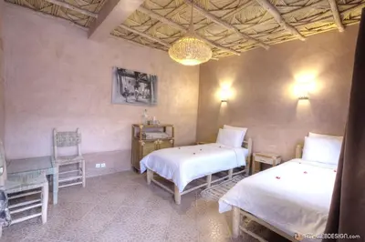 a bedroom with two beds and a table and chairs at Guest House Bagdad Café in Aït Ben Haddou