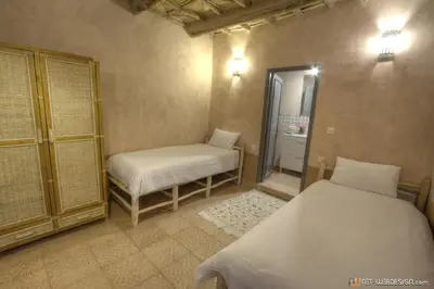 a bedroom with two beds and a bathroom with a mirror at Guest House Bagdad Café in Aït Ben Haddou