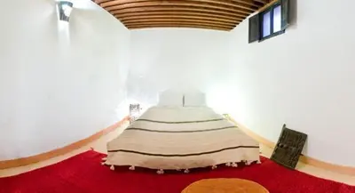 a large bed in a room with a red carpet at Riad La Maison D'à Côté in Meknès
