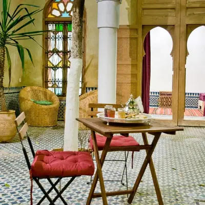 a table and two chairs in a room at Riad La Maison D'à Côté in Meknès