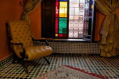 a room with a chair and a stained glass window at Dar Anebar in Fès