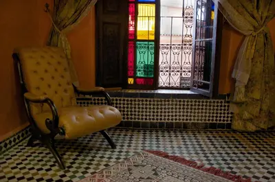 a room with a chair and a stained glass window at Dar Anebar in Fès