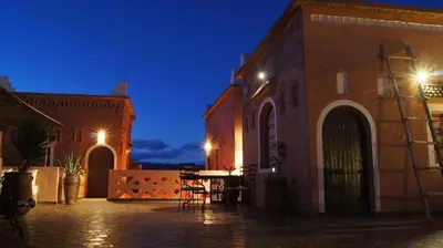 a building with a table in a courtyard at night at Kasbah Isfoula and spa in Aït Ben Haddou