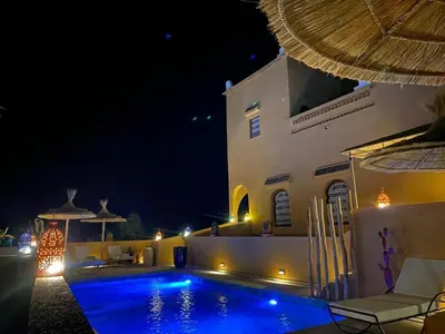 a swimming pool in front of a building at night at Kasbah Isfoula and spa in Aït Ben Haddou