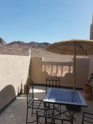 a table and chairs and an umbrella on a patio at Résidence MARWA in Ouarzazate