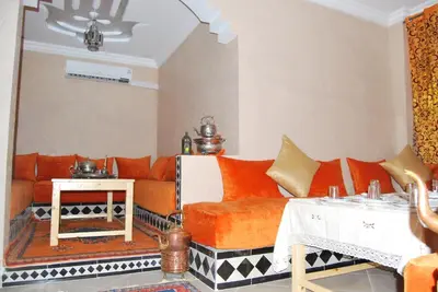 a living room with an orange couch and a table at Résidence MARWA in Ouarzazate