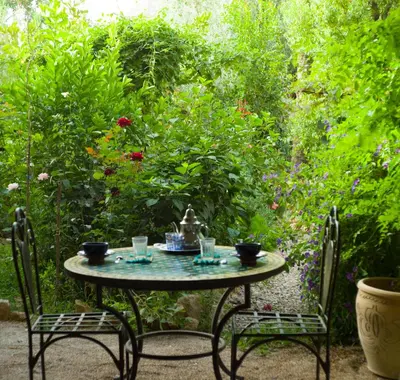 a table with two chairs and a tea kettle on it at A Secret Garden in Tinerhir