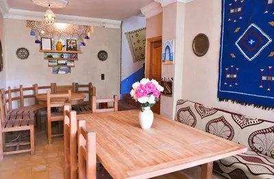 a dining room with a table and a vase with flowers on it at A Secret Garden in Tinerhir