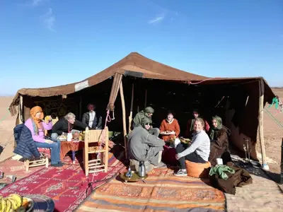 a group of people sitting in a tent in the desert at Camp Iguidi Tours in Mhamid
