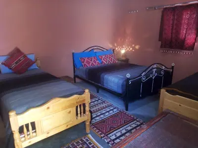 a bedroom with two beds and a rug at Ecolodge du Draa in Ouled Otmane