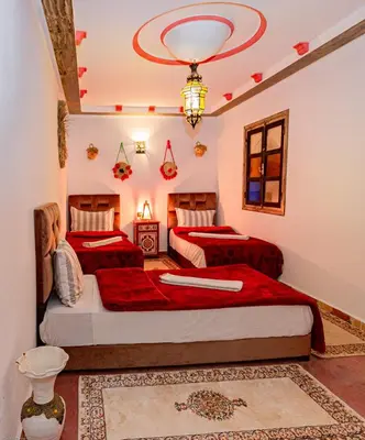 a bedroom with two beds and a chandelier at Dar Soulaimane in Marrakech
